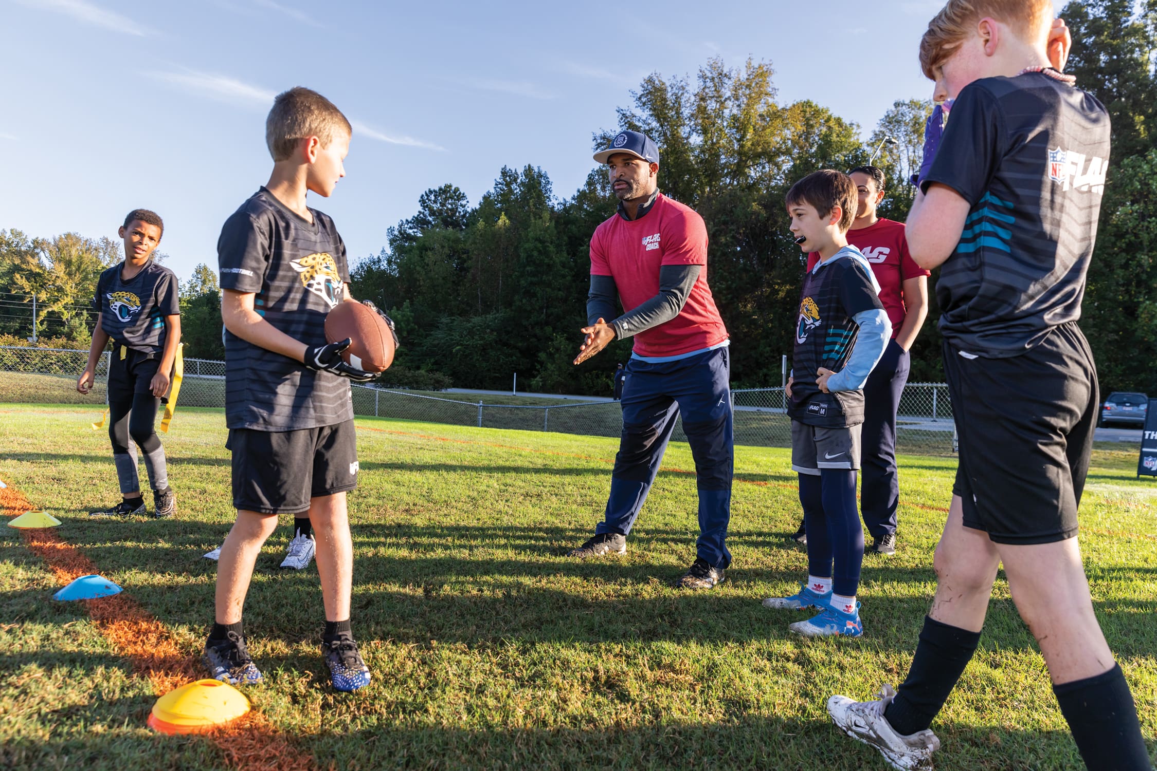 Youth flag football players gather around their coach