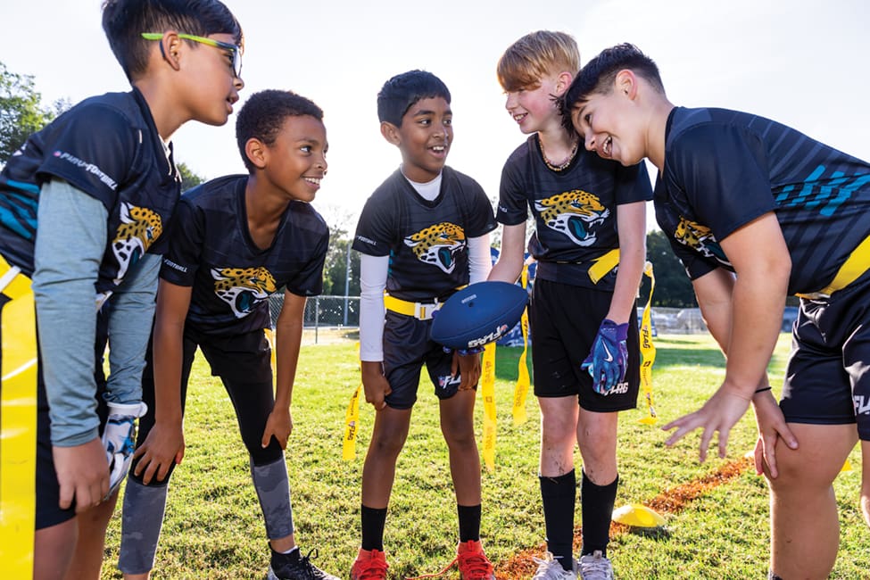 Youth flag football players huddle up.