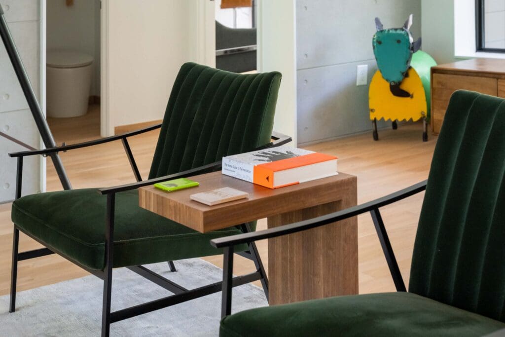 A colorful art piece sits behind two velvet green chairs in the home's living space. 
