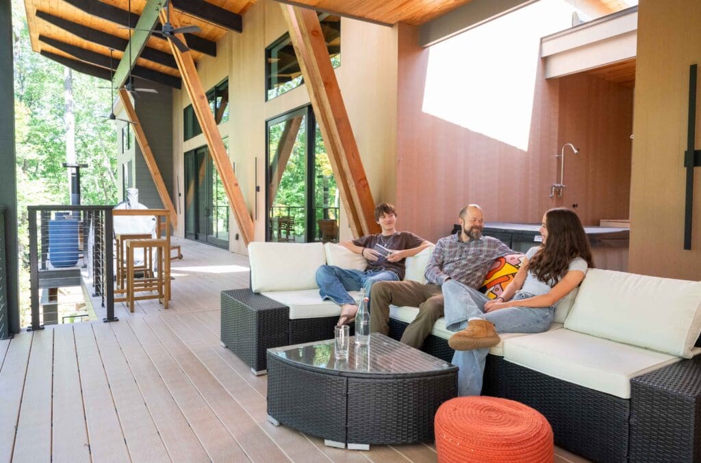 Jason and his two children sit on a couch on their back deck together. 