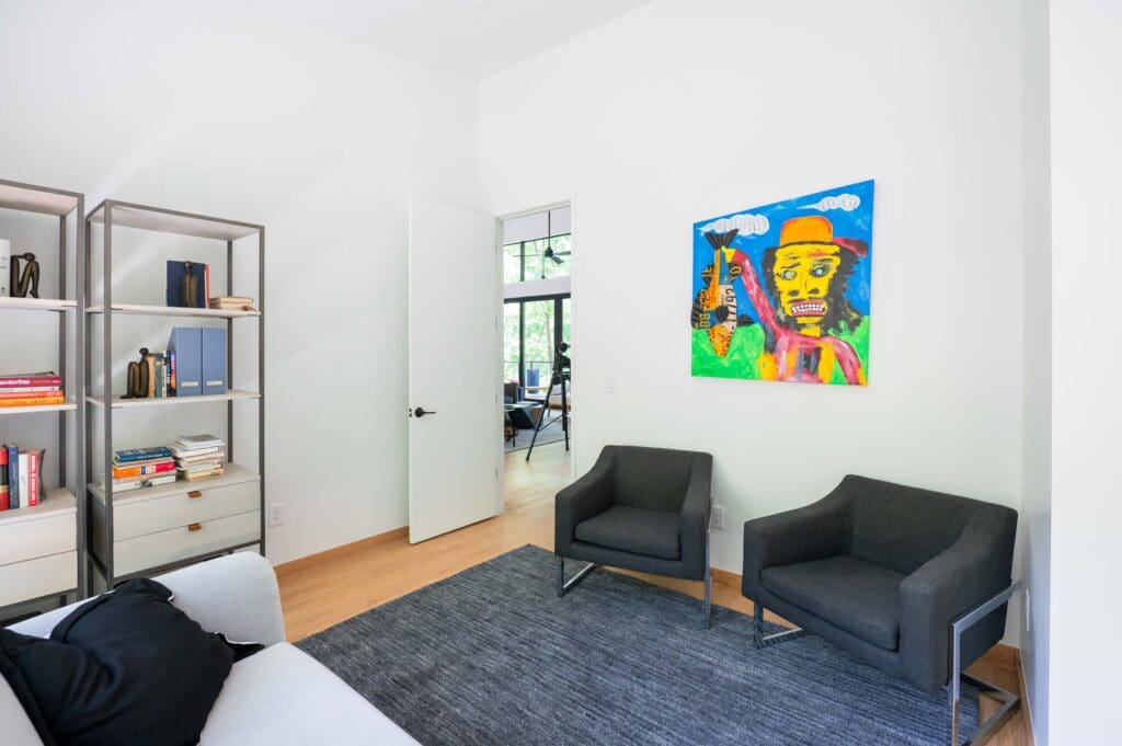 A seating area of the home is brightened up with a colorful folk art painting. 