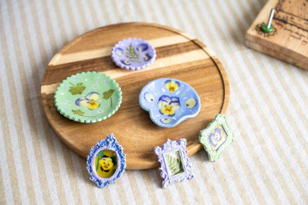 Pressed pansy flowers displayed in trinket dishes and miniature frames.
