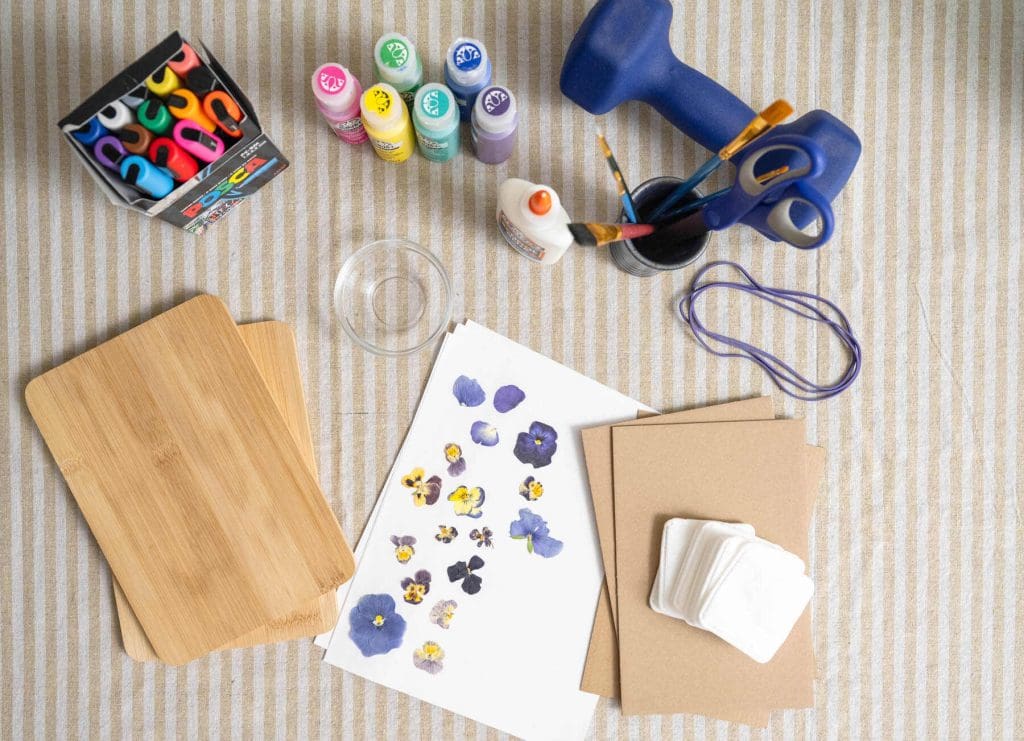 Materials for pressing flowers and leaves, including wooden boards, paper, glue, cotton pads, paints, brushes, markers and pressed flowers.