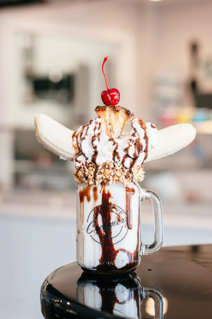 Banana split milkshake topped with whipped cream, chocolate syrup and a cherry at Creative Creamery.