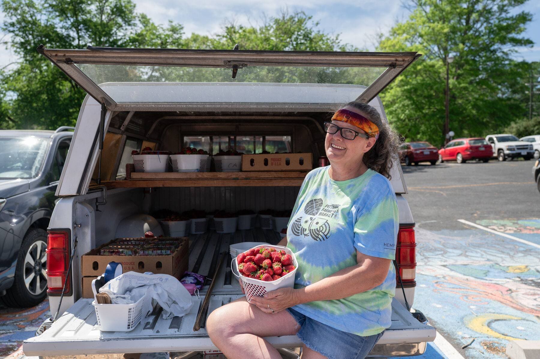 Greta Laws of McNeill Farms holds a bucket of their strawberries while sitting in the back of her car. 