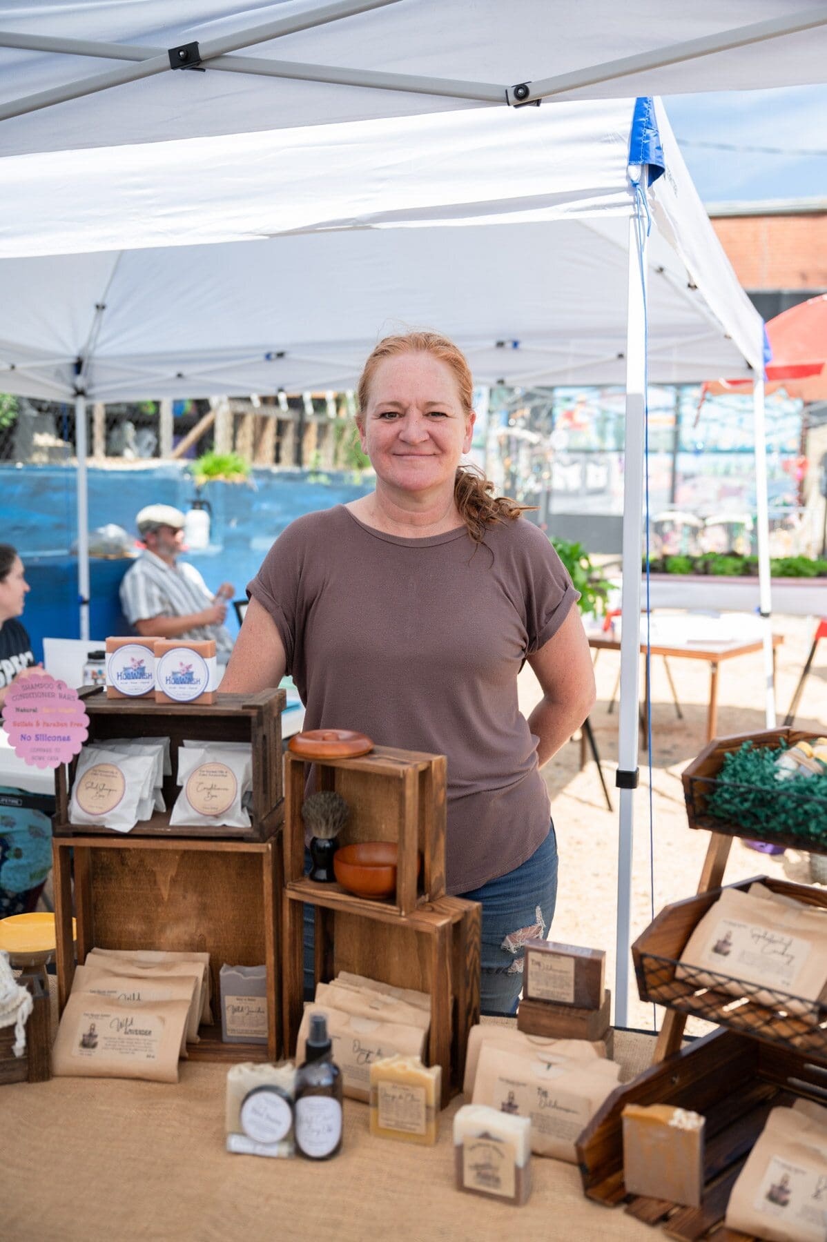 Tiffany Reischl of Toad Hollow Soapery poses for a portrait behind her soaps at the Pittsboro Farmer's Market. 
