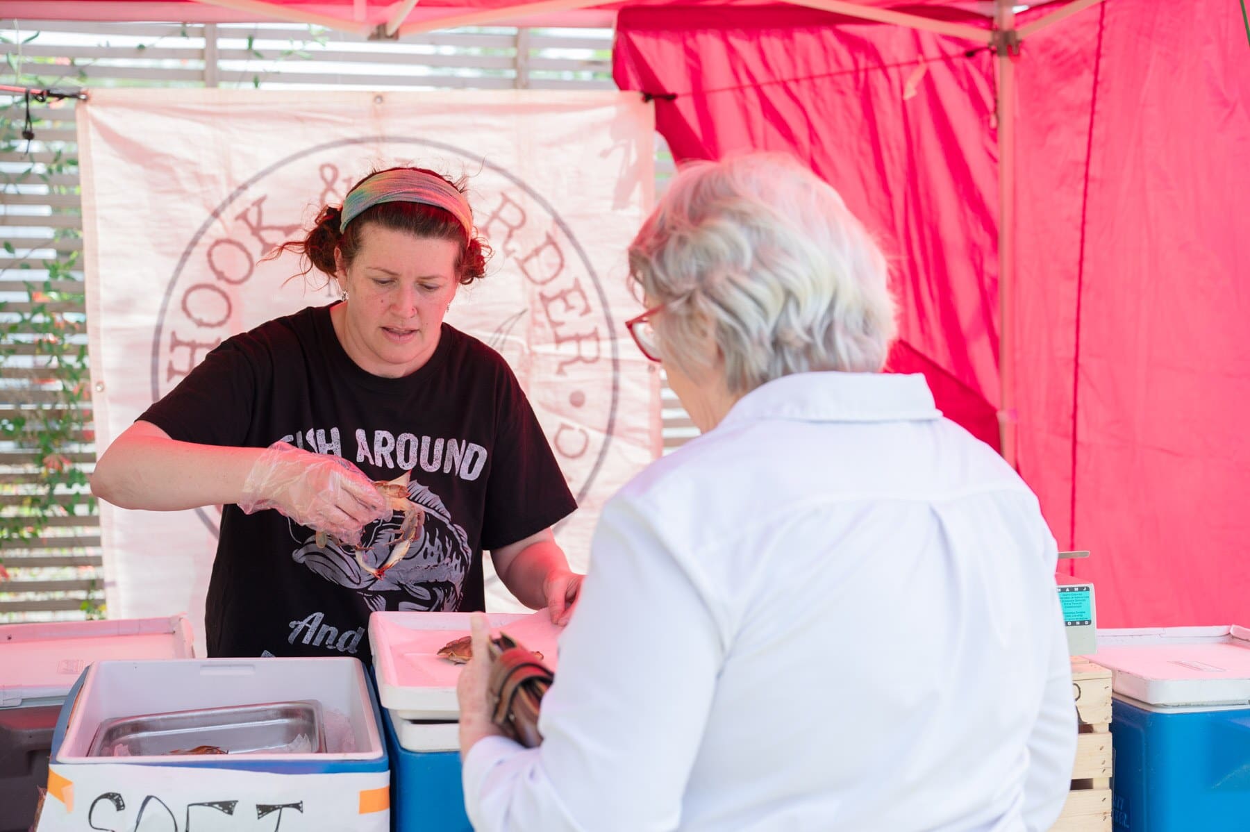 Amanda Jones of Hook & Larder weighs crabs under their tent at the Pittsboro Farmer's Market while a customer waits. 