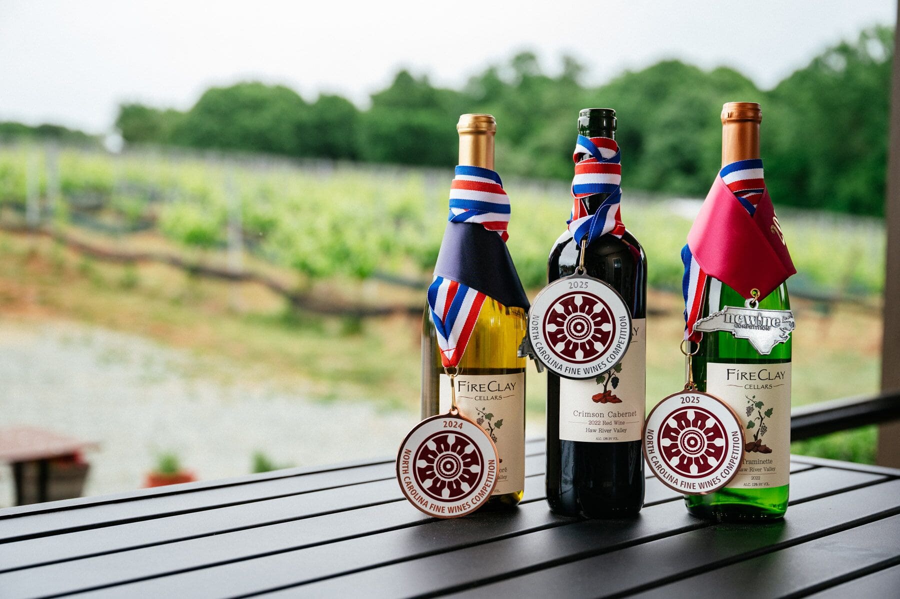 Three wine bottles with medals handing around their necks. 