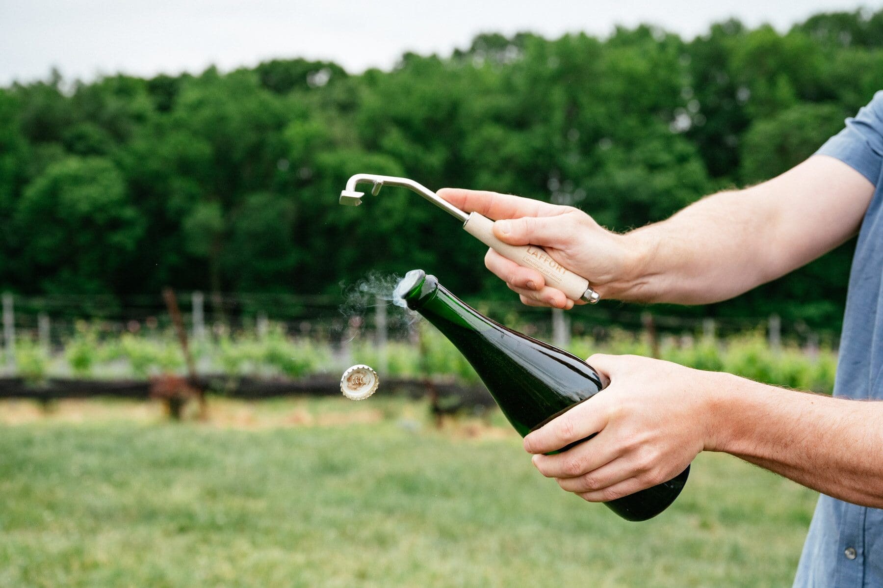 Someone popping the lid off of a wine bottle. 