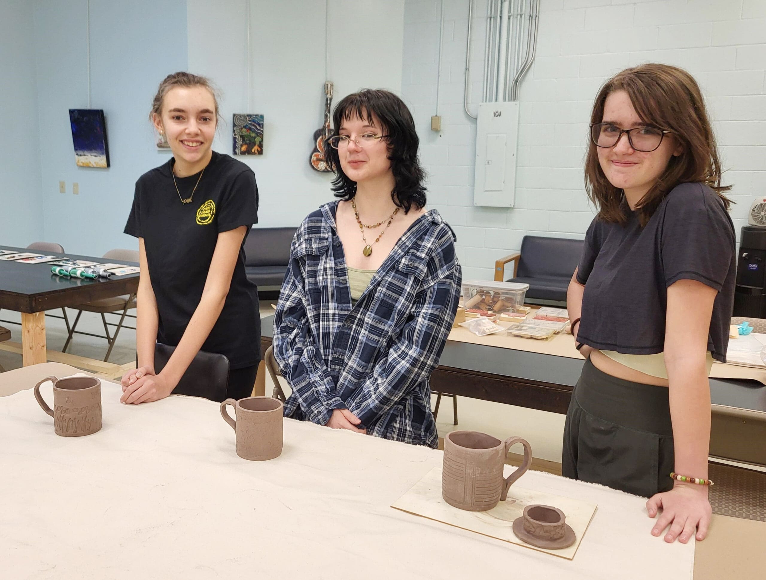 Three teenagers show off their ceramic pottery pieces they hand-crafted at Chatham Arts Center.