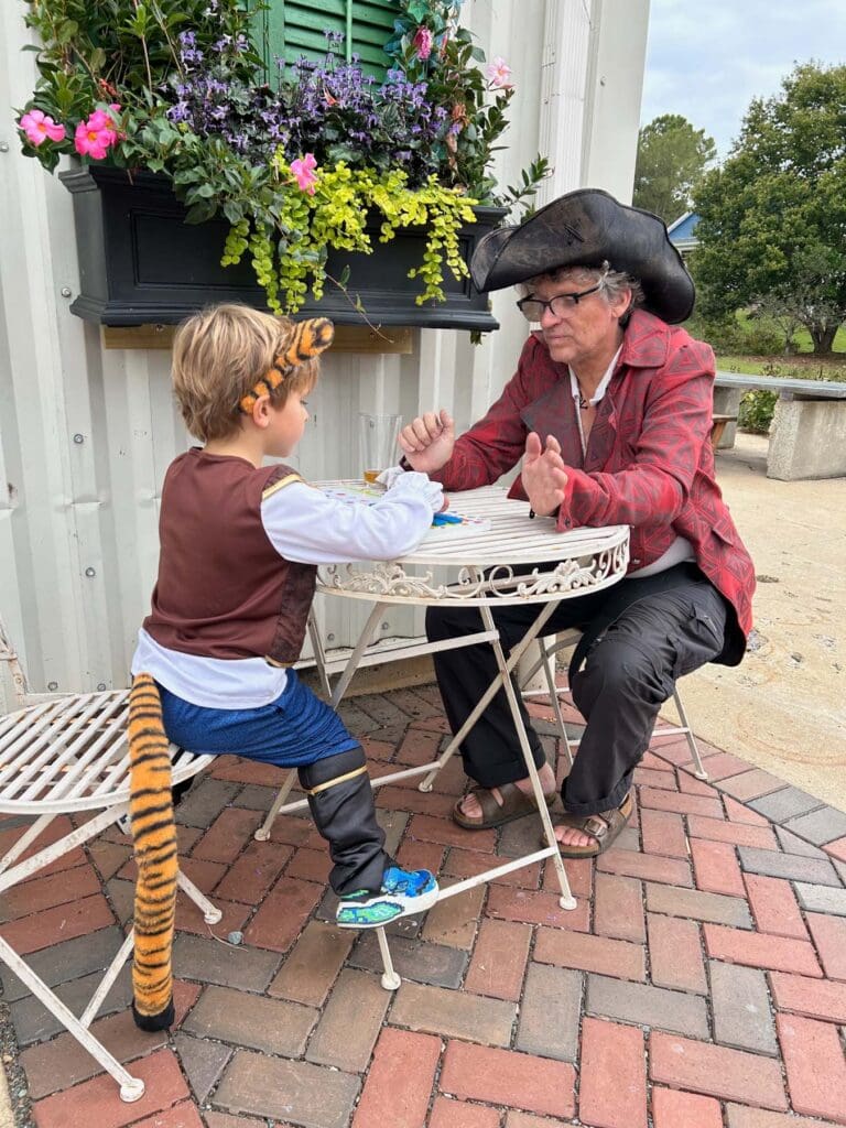 A man and a kid sit at a table outside doing an activity.